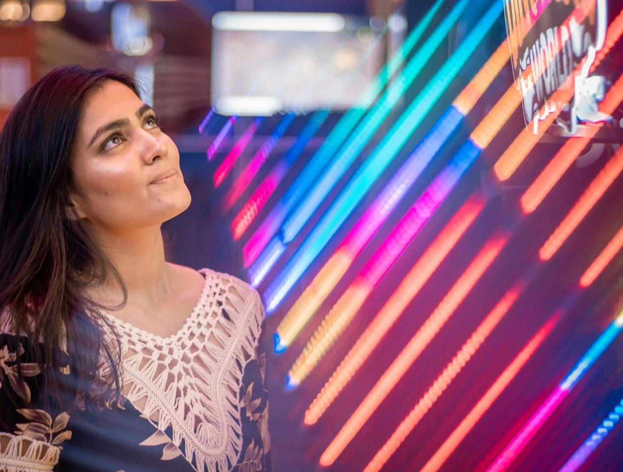 Young Indian woman surrounded by bright neon lights, representing modern glamour and the women who shaped Bollywood screen history